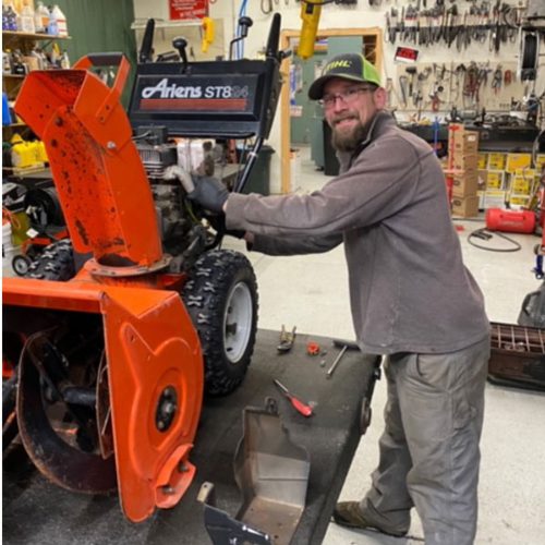 A staff member fixing a snow blower inside of Lucy Hardware.