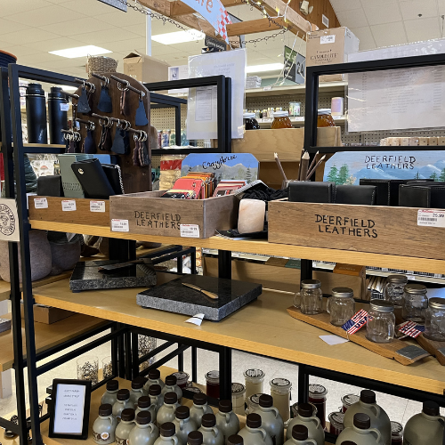 Wooden shelves display leather goods, thermal bottles, and small jars in a store. Signs read 